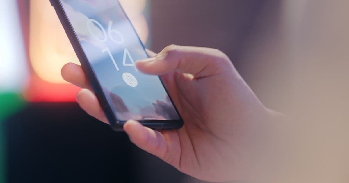 Una mano desbloquea un teléfono móvil con el lector de huellas de la pantalla